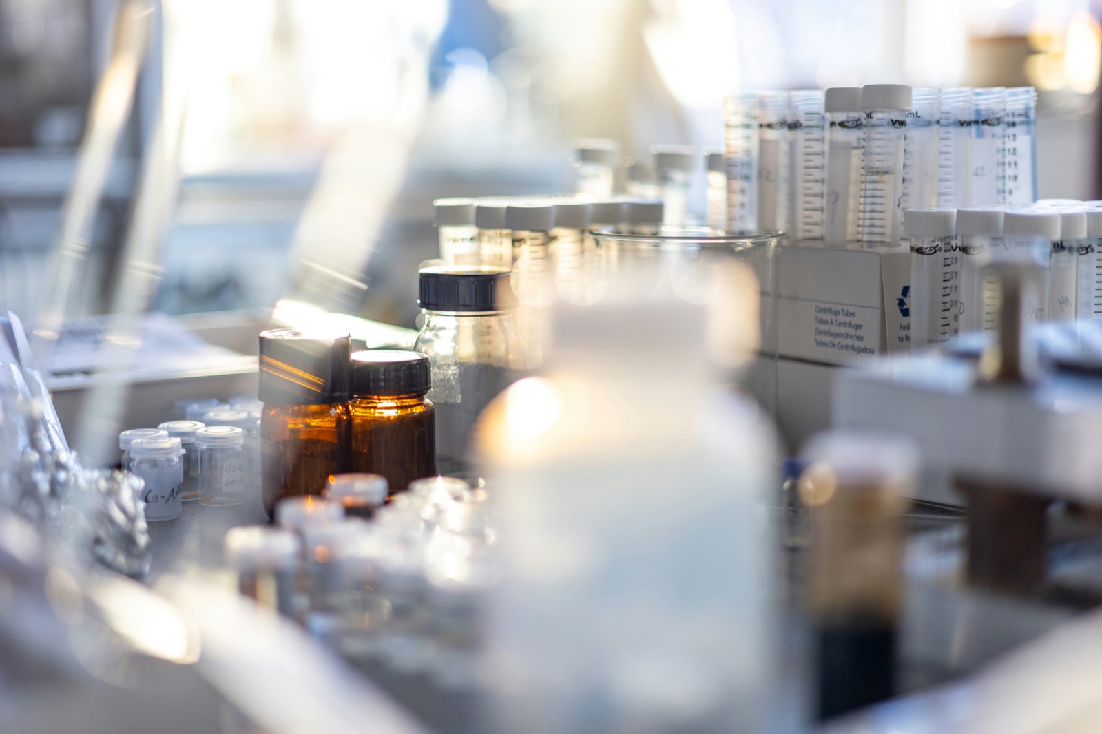Amber reagent bottles and racks of centrifuge tubes on a laboratory bench.