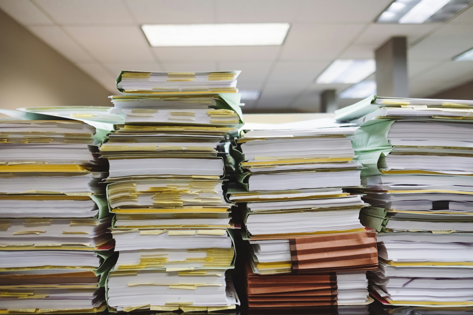 Deep stacks of tabbed and annotated paper files on a desk.